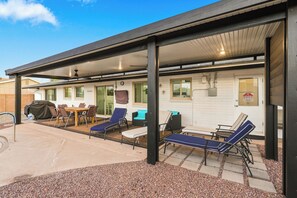 A covered outdoor patio with seating and a barbecue grill.