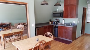 A compact kitchen with wooden cabinets, a microwave, and a sink. - Large Brighton area studio  (Brighton)