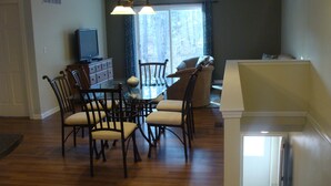 A dining area with a wooden table and chairs, a television, and a window with curtains. - 2 Bedroom, Full Kitchen, Dining Room, Living Room, Large Deck, Jacuzzi -Sleeps 8 (Benzonia)