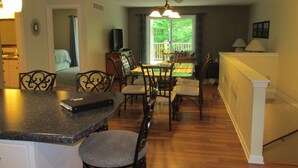 A dining area with a table and chairs, a kitchen area with a counter and chairs, and a living area with a sofa and television. - 2 Bedroom, Full Kitchen, Dining Room, Living Room, Large Deck, Jacuzzi -Sleeps 8 (Benzonia)