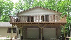A two-story house with a balcony, two attached garages, and a covered driveway. - 2 Bedroom, Full Kitchen, Dining Room, Living Room, Large Deck, Jacuzzi -Sleeps 8 (Benzonia)