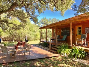 A wooden cabin with a porch, outdoor seating, and a barbecue grill. - Secluded Ranch Cabin between Garner and Lost Maples (Utopia)