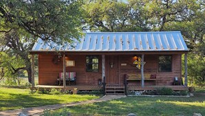 A rustic cabin with a metal roof, wooden exterior, and a porch with seating.