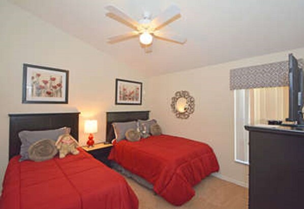 A bedroom with two beds, a ceiling fan, and framed artwork on the walls.