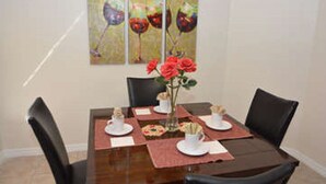 Een eettafel gedekt met borden, bekers en een bloevas.