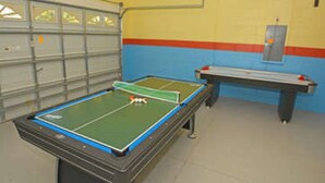 Een tafeltennistafel met een net in het midden, een klein tafeltennistoestel, en een metalen rek.