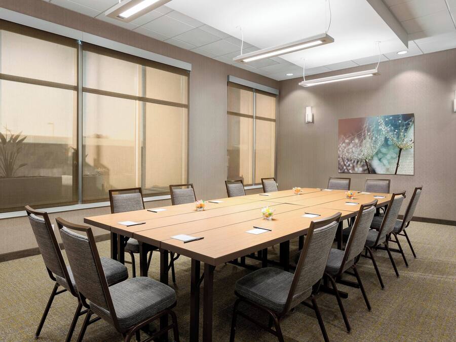Una sala de conferencias con una mesa grande, sillas y ventanas amplias.