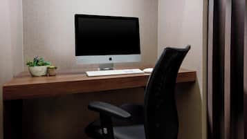 A modern office desk with a computer, keyboard, and a chair.