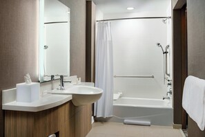 Un baño moderno con lavamanos, espejo y bañera.