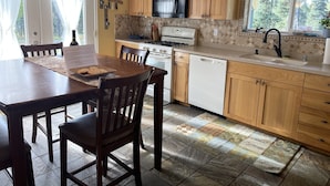 A kitchen with wooden cabinets, a stove, a microwave, and a dishwasher. - Friendly Reeder Lake House (Kasilof)