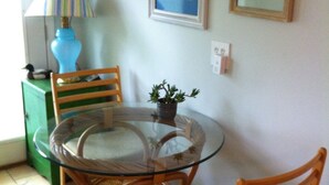 A dining area with a glass table surrounded by wicker chairs, a blue lamp, and framed artwork on the wall. - RIVERKEEPER INN, Waterfront Property on the Potomac River   (Harper's Ferry)
