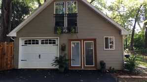 A single-story house with a garage, a front door, and a small balcony with plants. - RIVERKEEPER INN, Waterfront Property on the Potomac River   (Harper's Ferry)
