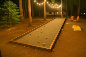 Una cancha de croquet con marco de madera, cerco de malla y algunas bolas de croquet en el suelo.