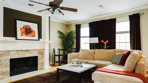 Una sala de estar con chimenea, un sofá, una mesa de centro y un ventilador de techo.