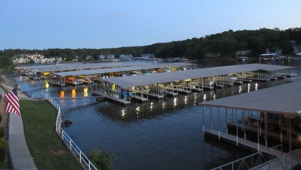 A waterfront marina with multiple docks and boats, surrounded by residential buildings and greenery. -  UPDATED LAKEFRONT WALK-IN UNIT, 2 POOLS, BEACH, DECK (Osage Beach)