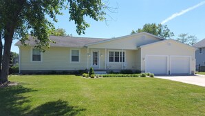 A single-story house with a front porch, two garage doors, and a well-maintained lawn. - Quiet convenient location! Remodeled 4br 3ba. Dog friendly, huge deck, hot tub . (Ocean View)