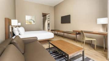 Ett modernt hotellrum med en säng, en soffa, ett skrivbord och en tv.