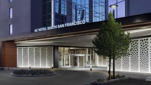 Exterior del Hotel AC South San Francisco, con una fachada moderna, amplios ventanales de vidrio y una entrada bien iluminada.