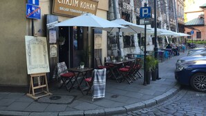 An outdoor café with tables and chairs, a menu board, and a sign for 'Chajim Kohan'. - Loft 1910 - Kazimierz Echoes (Kraków)