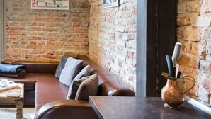 A cozy room with a brick wall, a brown leather sofa, a wooden coffee table, and a copper pitcher on a dark countertop. - Loft 1910 - Kazimierz Echoes (Kraków)