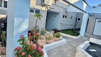 Een binnentuin met potplanten, een kleine tuin en een gebouw met meerdere ramen en airconditioners.