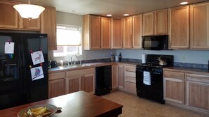 A kitchen with wooden cabinets, a black refrigerator, a microwave, a stove, and a sink. - Downtown Pagosa Springs, within walking distance to everything (Pagosa Springs)