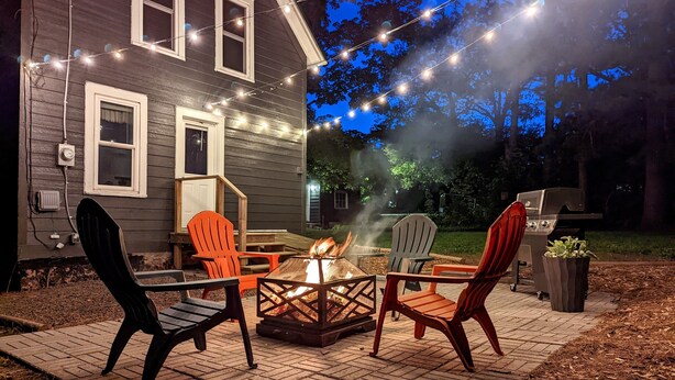 An outdoor patio with a fire pit, seating, and a grill.