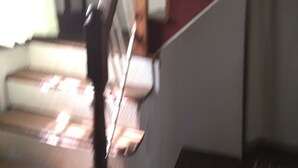 Una escalera de madera con barandilla que lleva a un rellano con alfombra roja.