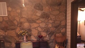Un comedor con pared de piedra, mesa de madera y sillas.