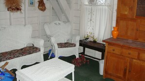 Une pièce meublée de meubles en osier blanc, avec une armoire en bois et une fenêtre donnant sur des arbres.