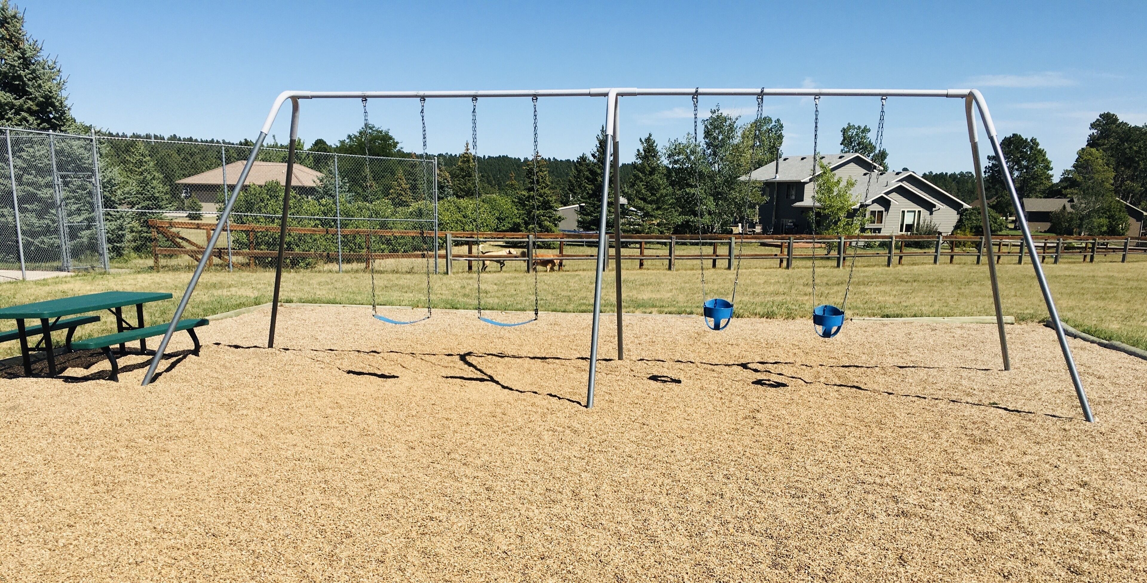 A playground with swings and a picnic table.