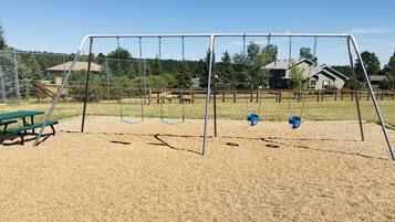 A playground with swings and a picnic table.