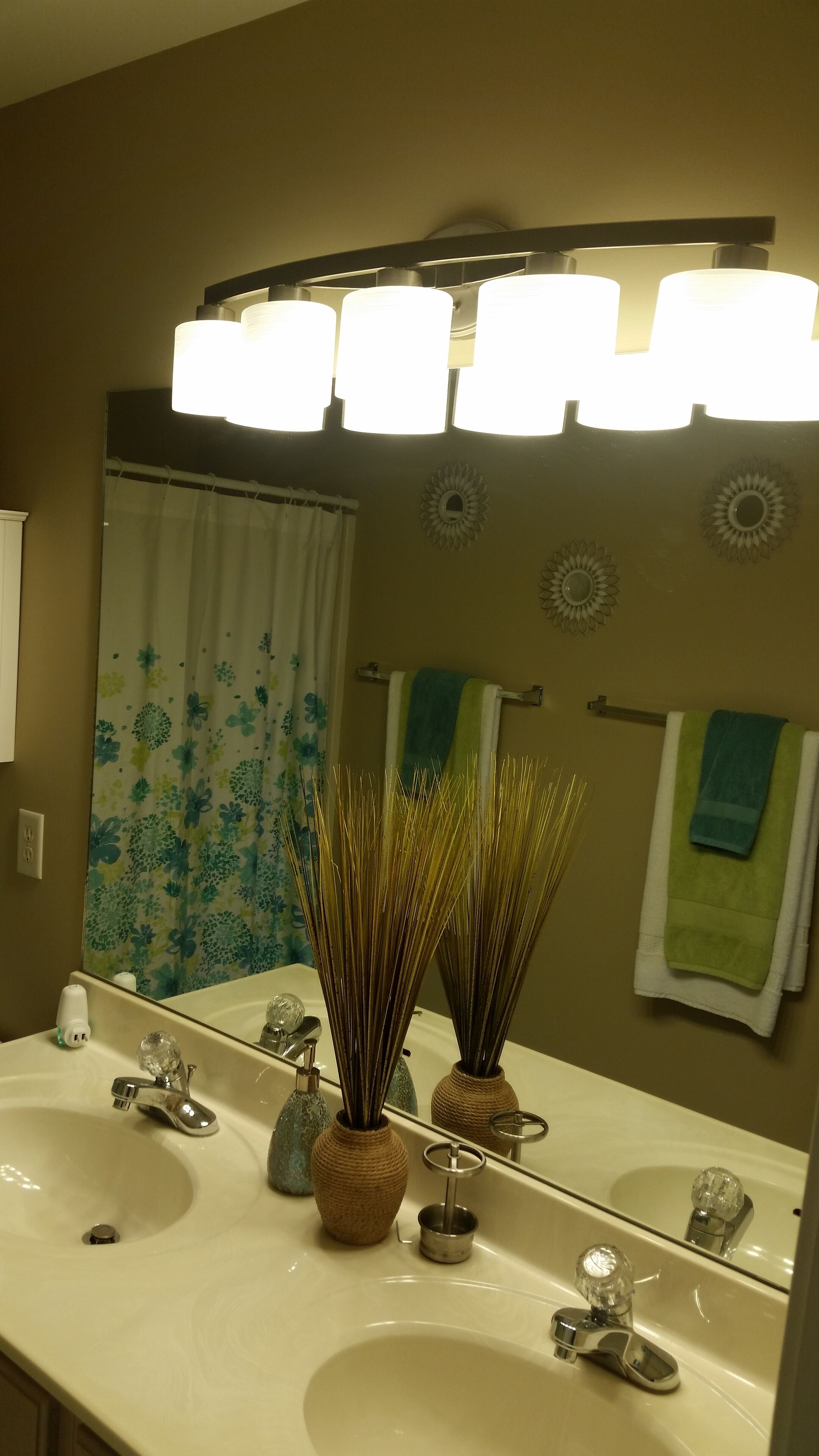 A bathroom with a large mirror, two sinks, a shower curtain, and a towel rack.
