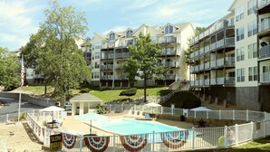 A residential building with multiple balconies, a swimming pool, and a flagpole with an American flag.