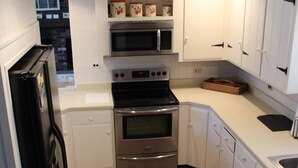 A kitchen with white cabinets, a stainless steel oven, a microwave, and a black refrigerator. - Perfect house for experiencing Mount Washington Valley year round! Pet Friendly! (North Conway)