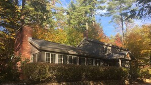 A two-story house with a stone wall and a large windowed front. - Perfect house for experiencing Mount Washington Valley year round! Pet Friendly! (North Conway)