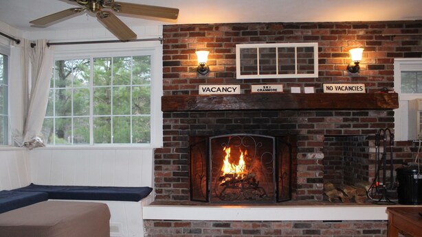 A room with a brick fireplace, a ceiling fan, a window with curtains, and a bed. - Perfect house for experiencing Mount Washington Valley year round! Pet Friendly! (North Conway)