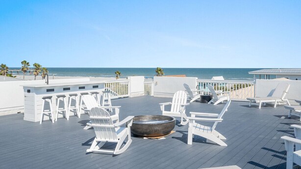 A rooftop terrace with white Adirondack chairs, a fire pit, and a view of the ocean. - Sol Mate-Elevator,Beach,Firepit rooftop,Arcade (St. Augustine)