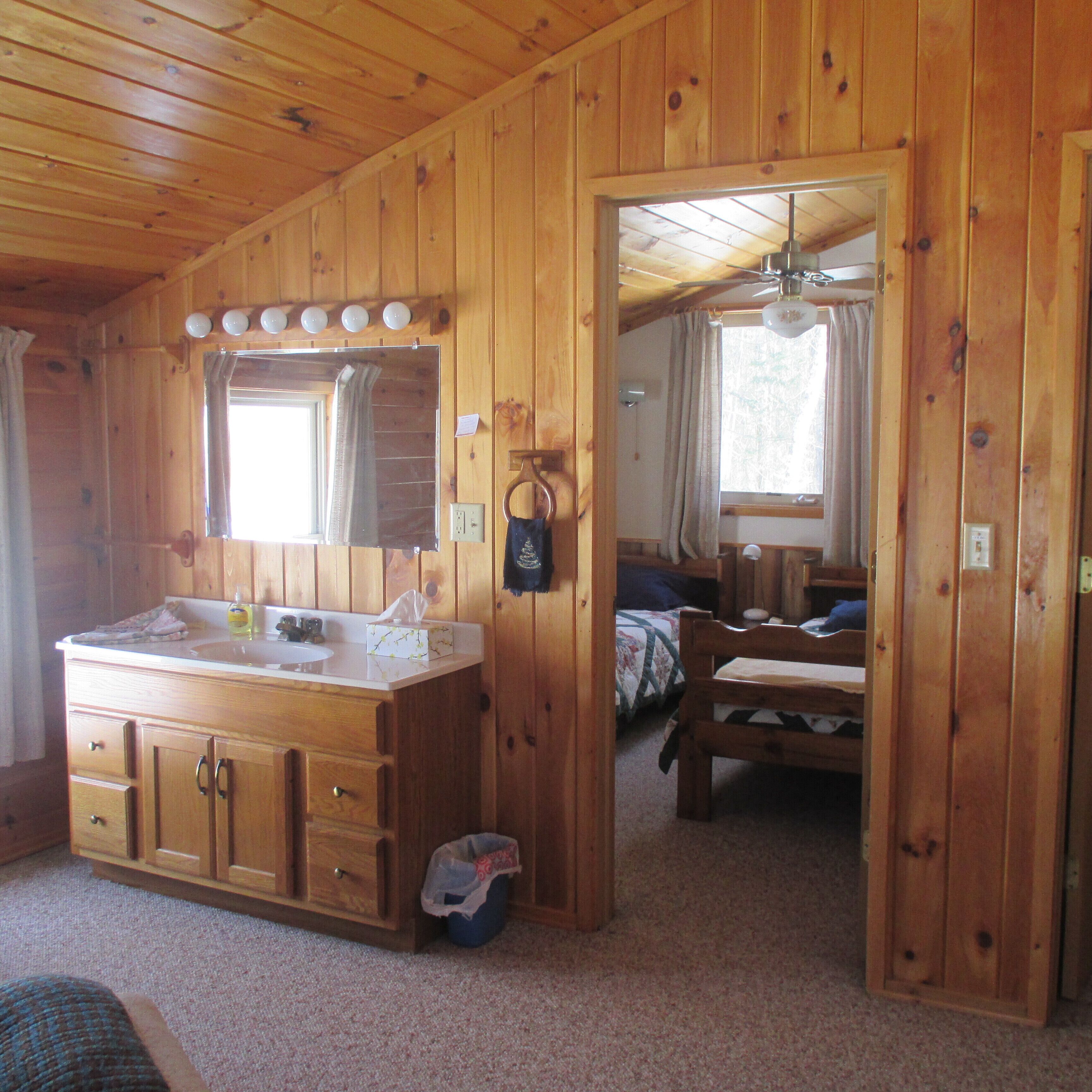L’intérieur d’une cabane en bois, avec une grande coiffeuse en bois, un lit et une petite table.