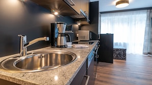 Una cocina moderna con un lavamanos de acero inoxidable, una cafetera y un microondas.