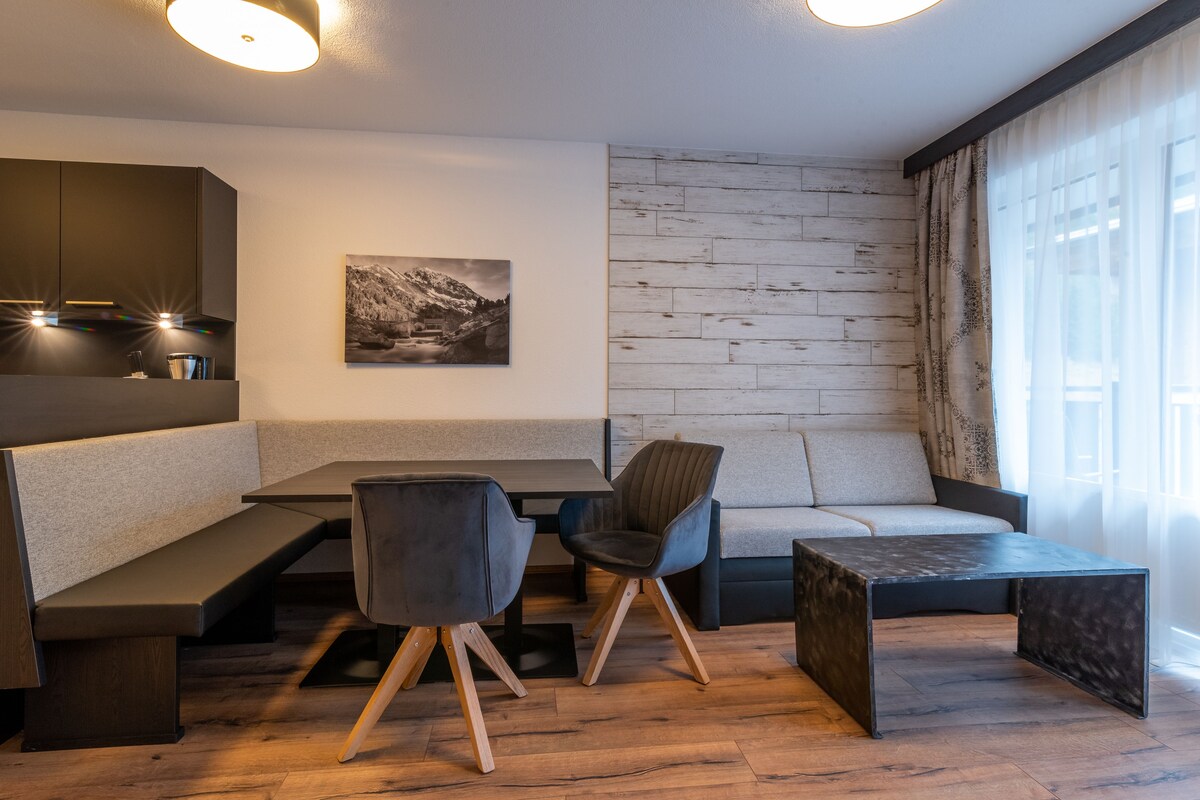 A modern dining area with a wooden bench seating, a table, and a sofa.