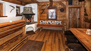 Un interior rústico de madera con chimenea de piedra, bancos de madera y un banco con cojines de cuero de vaca.