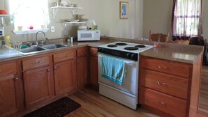A kitchen with wooden cabinets, a sink, a microwave, and a stove.
