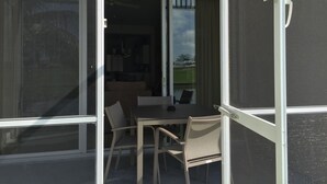 A room with a sliding glass door leading to an outdoor patio area. Inside, there is a dining table with chairs and a sofa. - Wonderful, spacious 3 bedroom, 2 bath unit, enjoy free Golfing this Summer (Naples)