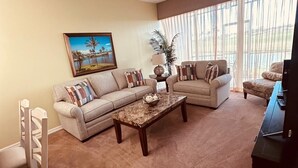 A living room with two sofas, a coffee table, a TV, and a painting on the wall. - Wonderful, spacious 3 bedroom, 2 bath unit, enjoy free Golfing this Summer (Naples)