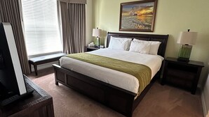 A hotel room with a bed, a ceiling fan, a painting, two bedside tables with lamps, and a window with curtains. - Wonderful, spacious 3 bedroom, 2 bath unit, enjoy free Golfing this Summer (Naples)