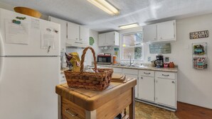 Une cuisine avec des meubles blancs, une table en bois et un panier.