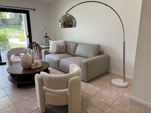Ein modernes Wohnzimmer mit einem Ecksofa, einem runden Couchtisch und einer Stehlampe.