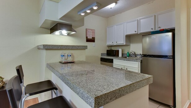 A kitchen with granite countertops, stainless steel appliances, and white cabinetry.