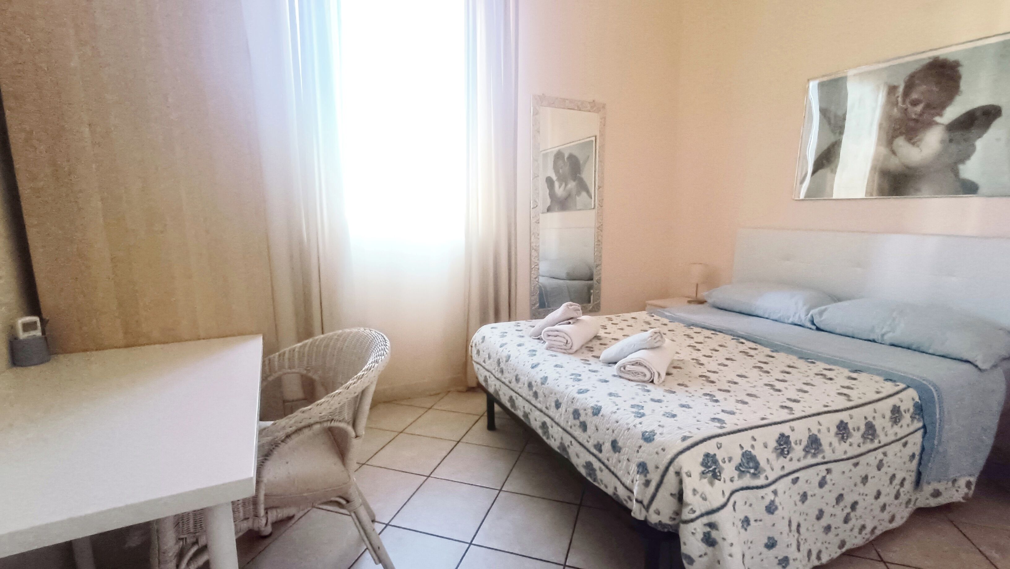 A hotel room with a bed, a chair, a desk, and a mirror.